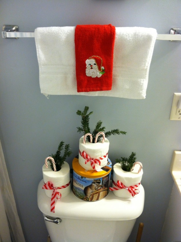 Inexpensive Christmas Bathroom Decorations with Red Santa Towel and Paper with Candy Cane and Pine Leaves with Red Ribbon over Toilet Tank 634x848 20 Amazing Christmas Bathroom Decoration Ideas